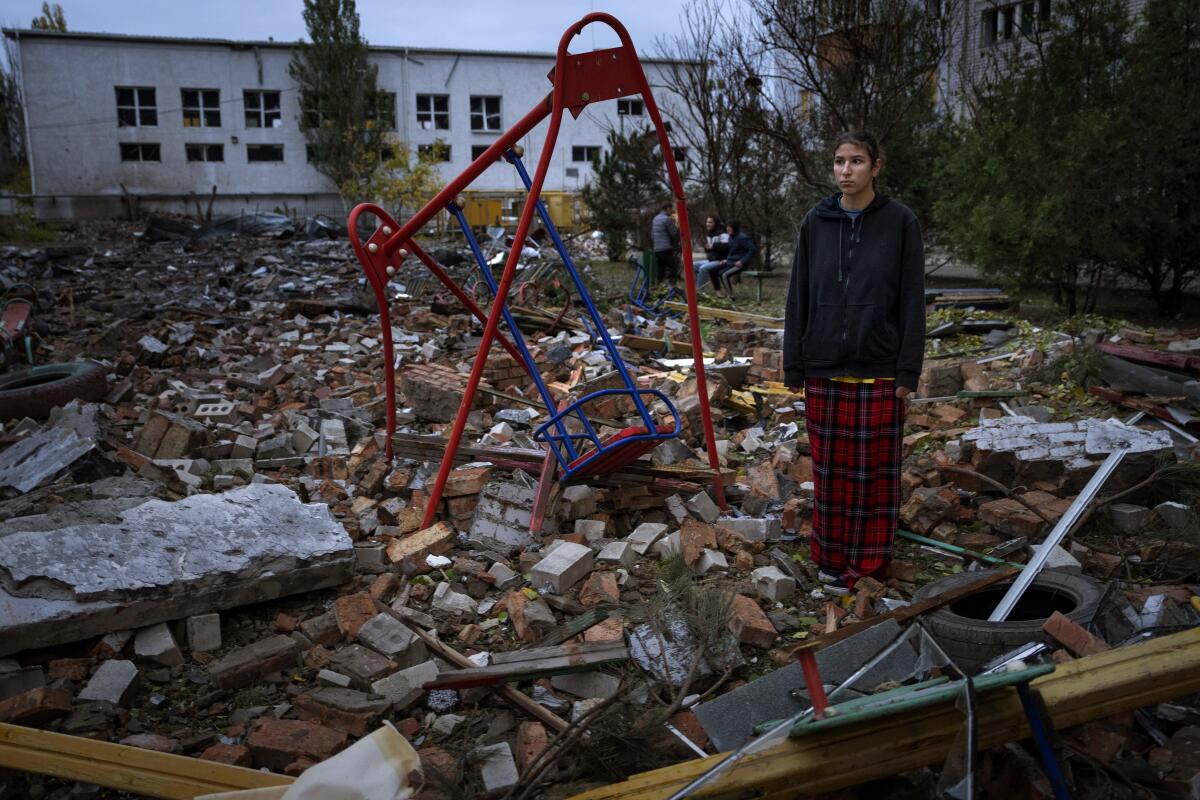 A teenager stands in the rubble of a destroyed playground.