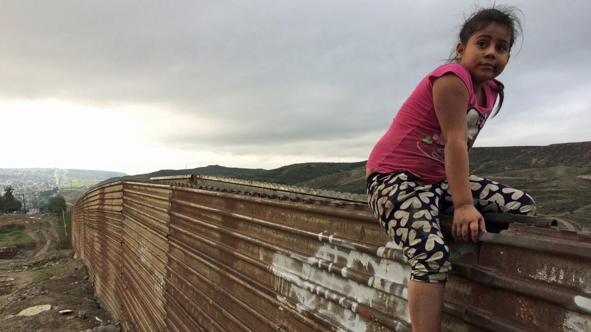 Sol, age 7, plays on the border wall, which stretches for miles into the western horizon.