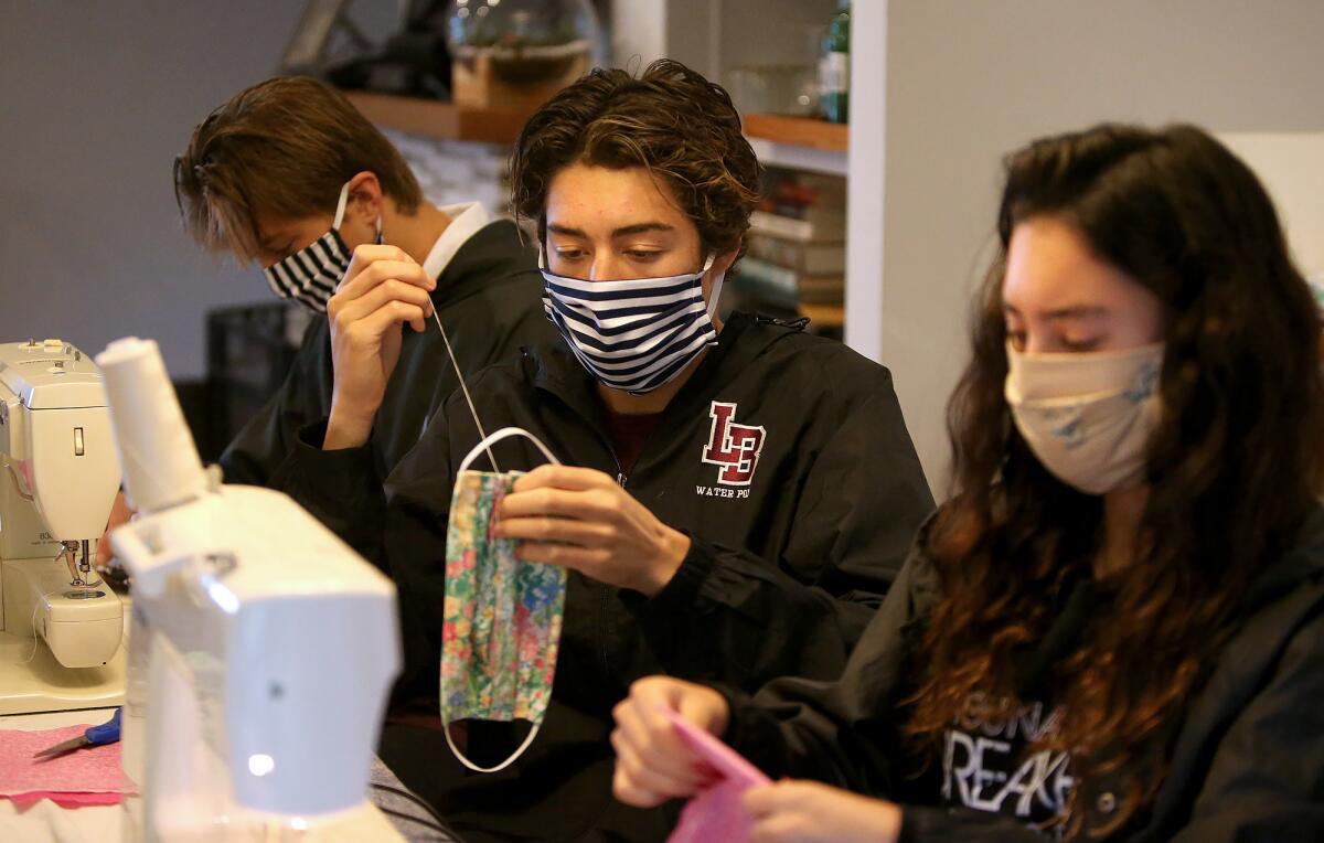 Laguna Beach High student-athletes Myha Pinto, Michael Pinto, and Jackson Golden, from right, sew and assemble homemade cotton masks for their "Sewing for SoCal" organization.