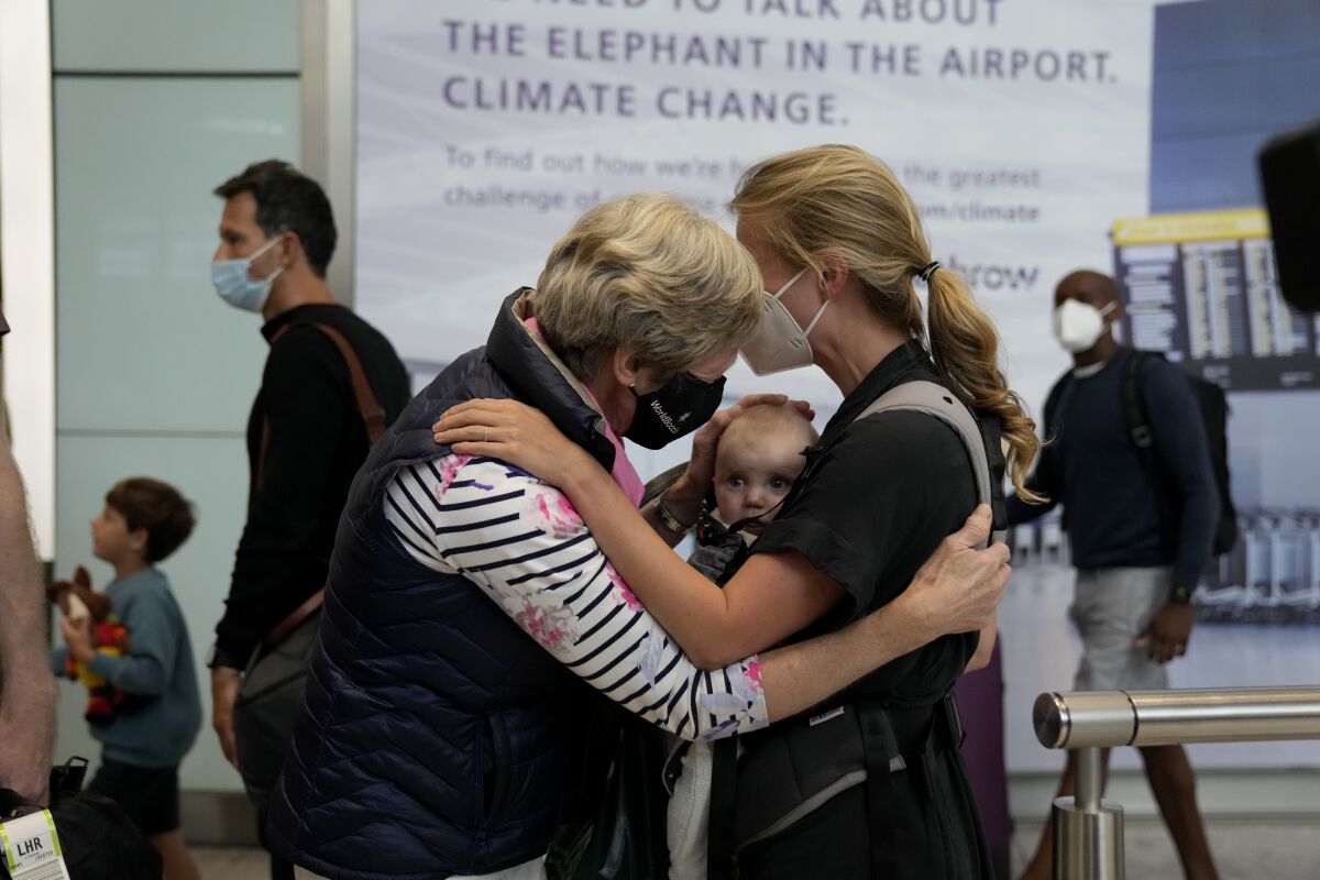 Susan Handfield, left, meets her baby granddaughter Charlotta for the first time, held by her mother Eva as they arrive from a Berlin flight at Terminal 5 of Heathrow Airport in London, Monday, Aug. 2, 2021. Travelers fully vaccinated against coronavirus from the United States and much of Europe were able to enter Britain without quarantining starting today, a move welcomed by Britain's ailing travel industry. (AP Photo/Matt Dunham)