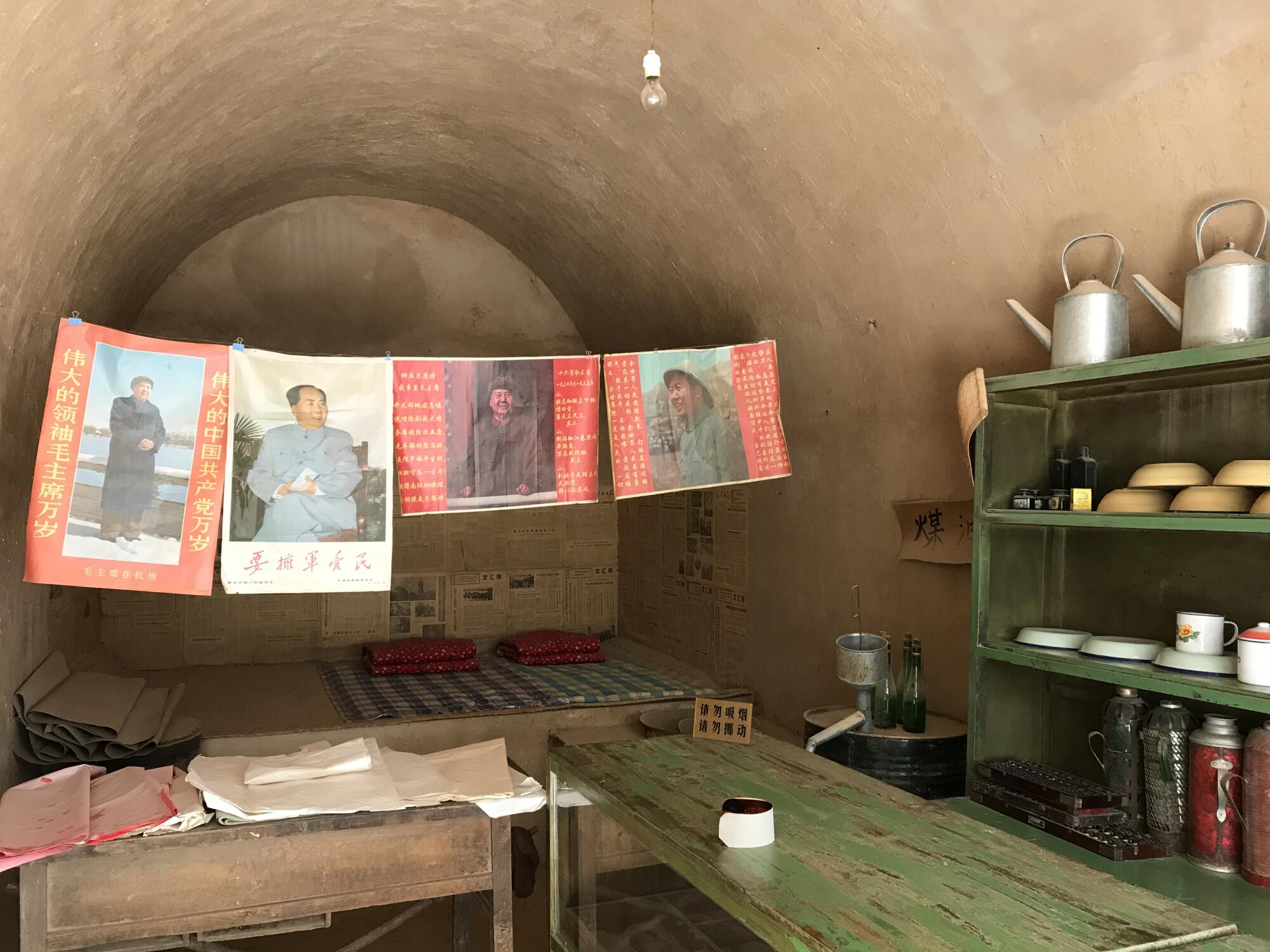 Posters of Mao Zedong hang a cave.