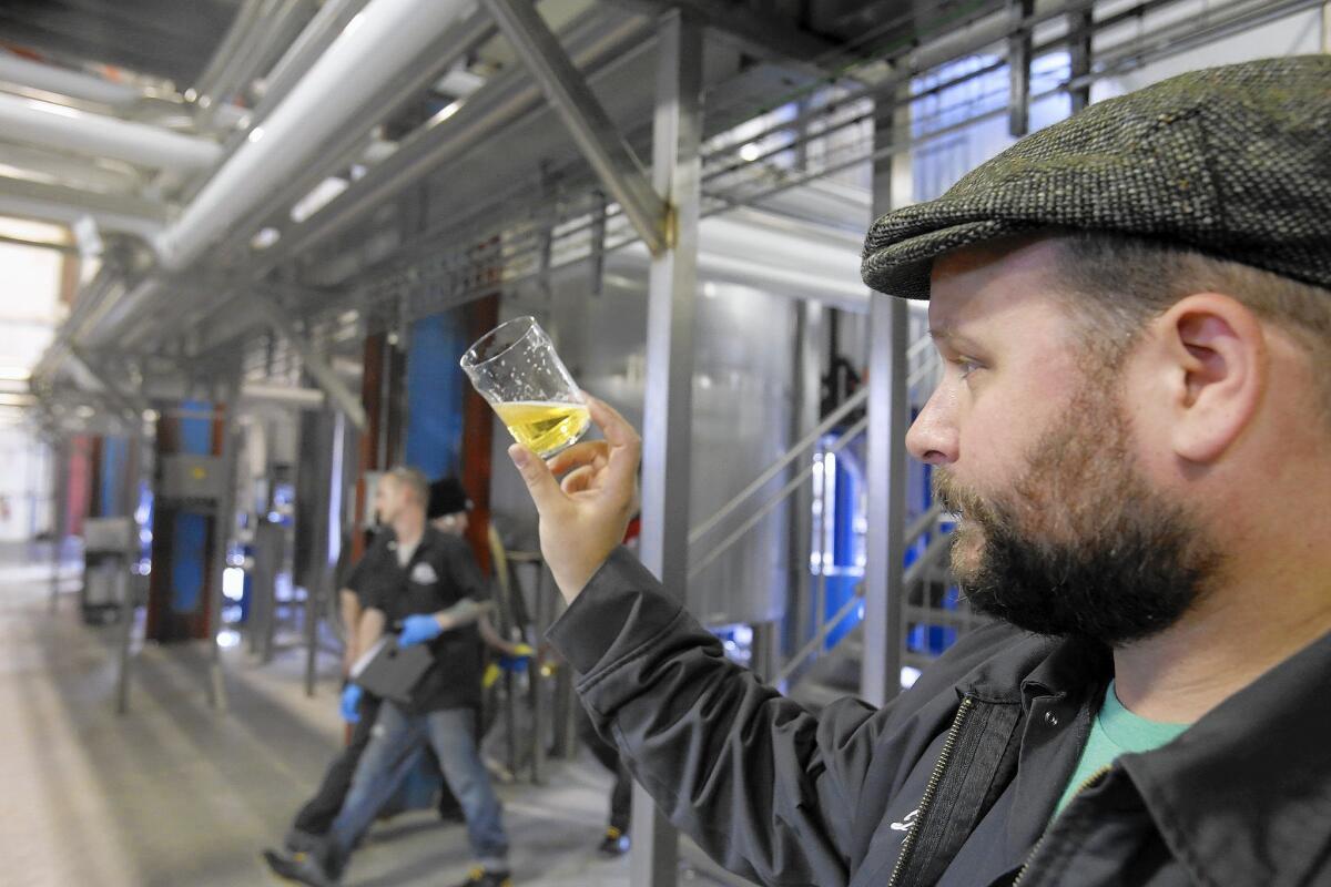 John Dunne checks a lager for clarity and carbonation at Golden Road Brewing, which would be hit with higher labor costs if L.A. were to raise its minimum wage.