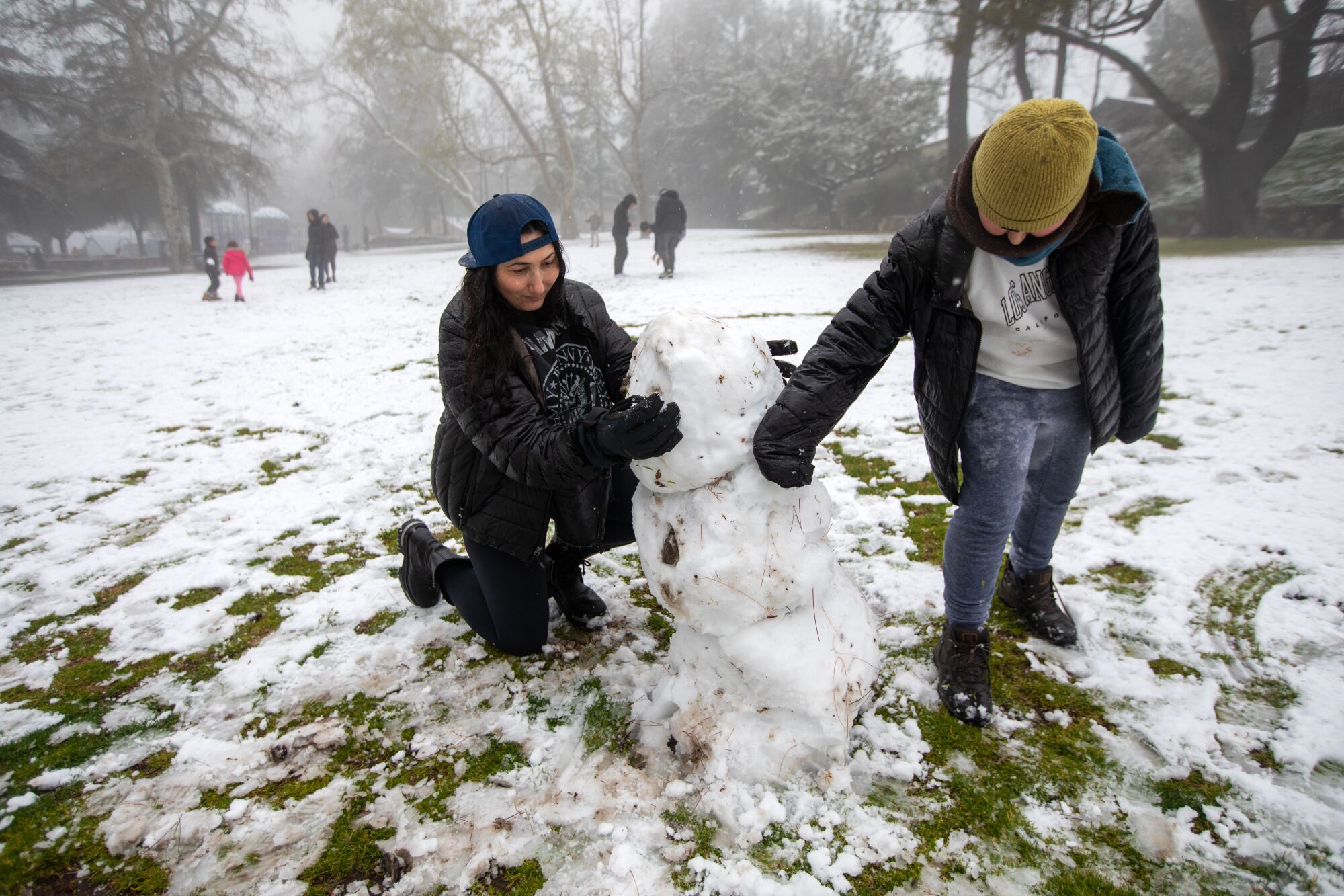 Lusin Torosyan, left, and her child Shant Yedigaryan, 12, build a snowman in Dunsmore Park in Glendale.