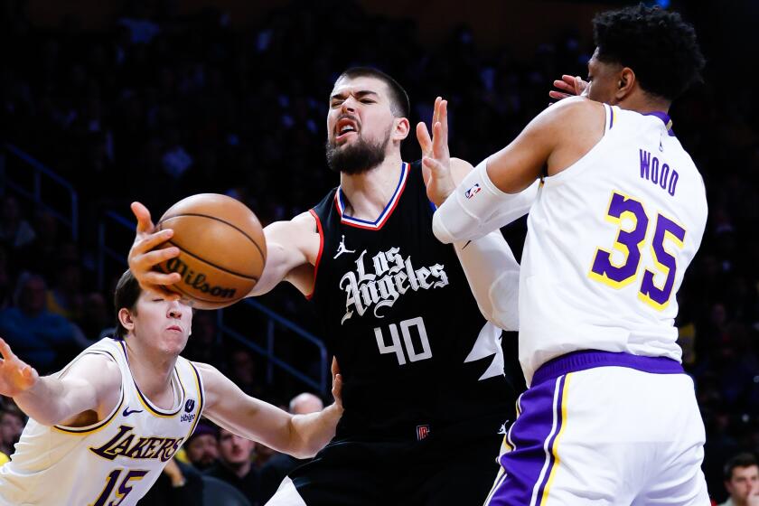 LOS ANGELES, CA - JANUARY 07: LA Clippers center Ivica Zubac (40) grabs onto a rebound between Los Angeles Lakers forward Christian Wood (35) and guard Austin Reaves (15) during the first half at Crypto.com Arena in Los Angeles Sunday, Jan. 7, 2024. (Allen J. Schaben / Los Angeles Times)