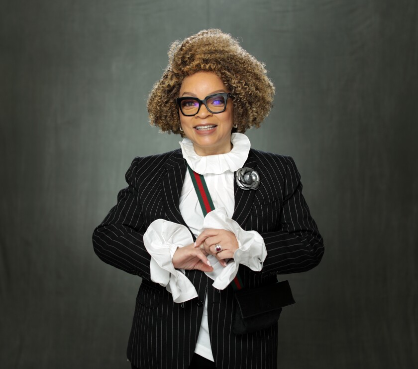 Ruth E. Carter posing in glasses and a pinstripe suit