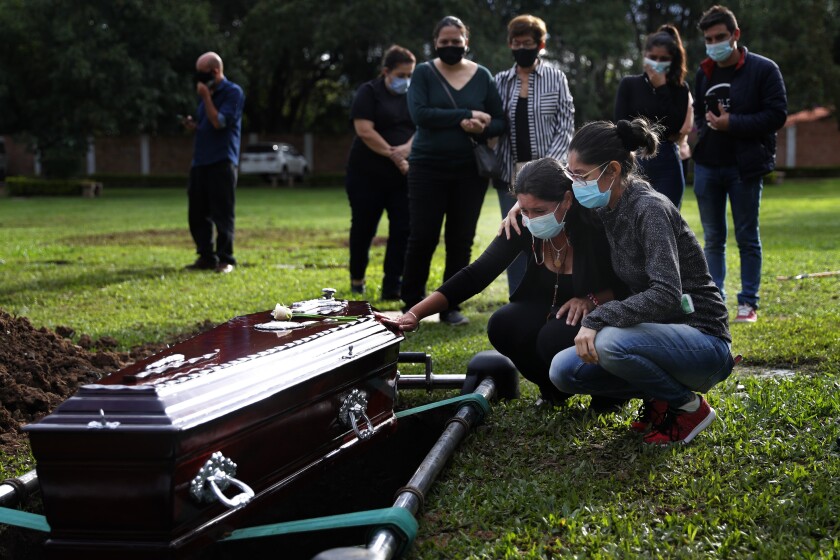Relatives mourn a victim of COVID-19, in Limpio, Paraguay, on Wednesday. 