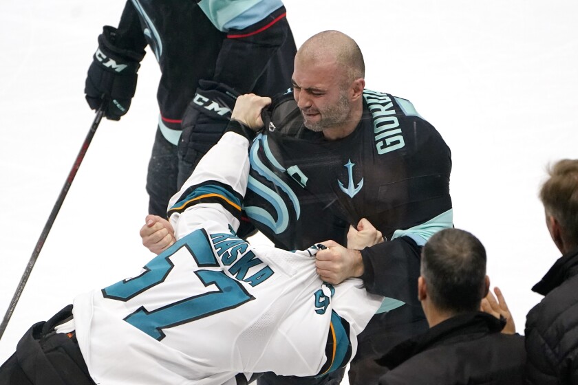 Seattle Kraken's Mark Giordano, right, grabs San Jose Sharks' Adam Raska as they tussle in the second period of an NHL hockey game Thursday, Jan. 20, 2022, in Seattle. (AP Photo/Elaine Thompson)
