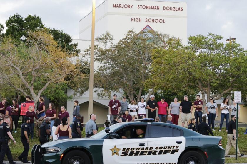 FILE - In this Feb. 28, 2018 file photo, a police car drives near Marjory Stoneman Douglas High School in Parkland, Fla., as students return to class for the first time since a former student opened fire there with an assault weapon. A Florida House committee voted Thursday, March 21, 2019, for a broad school safety bill that would expand an existing guardian program to allow classroom teachers to volunteer to carry weapons on campus if local school boards approve. The Republican-led legislation adopted 11-5 along party lines by the House Education Committee builds on a law passed after last year's mass shooting that killed 17 people at Marjory Stoneman Douglas High School. (AP Photo/Terry Renna, File)