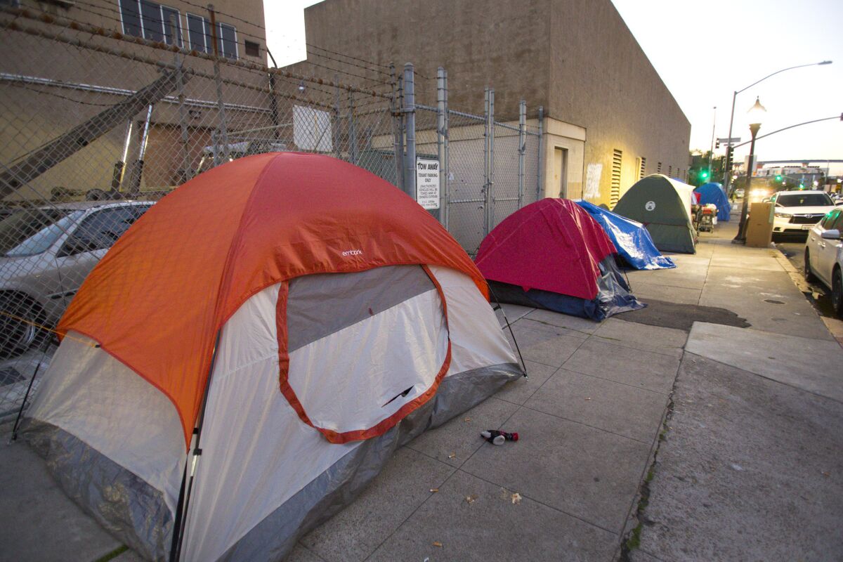 In this photo from March 2017, homeless people seek shelter in tents along a sidewalk in downtown San Diego. New enforcement guidelines will allow homeless people to have some property on the public right of way as long as it doesn't interfere with others who are trying to pass by.