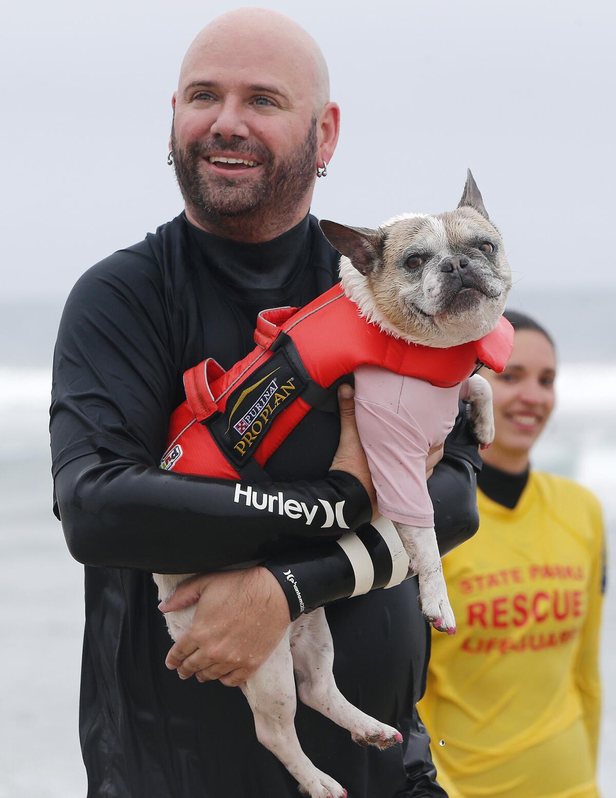 Dan Nykolayko of Newport Beach carries Cherie, a French bull dog, after they competed on Friday morning.