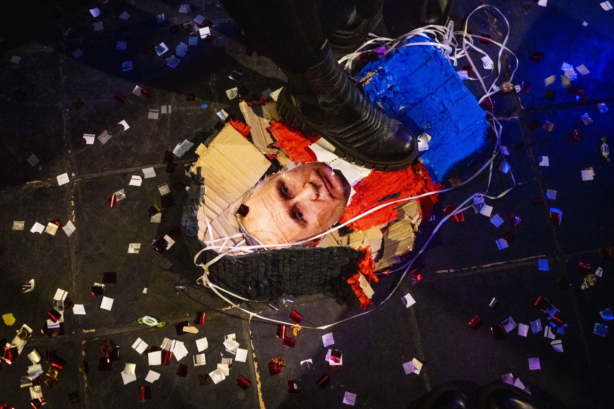 A smashed piñata featuring the face of Vladimir Putin on the floor of a bar 