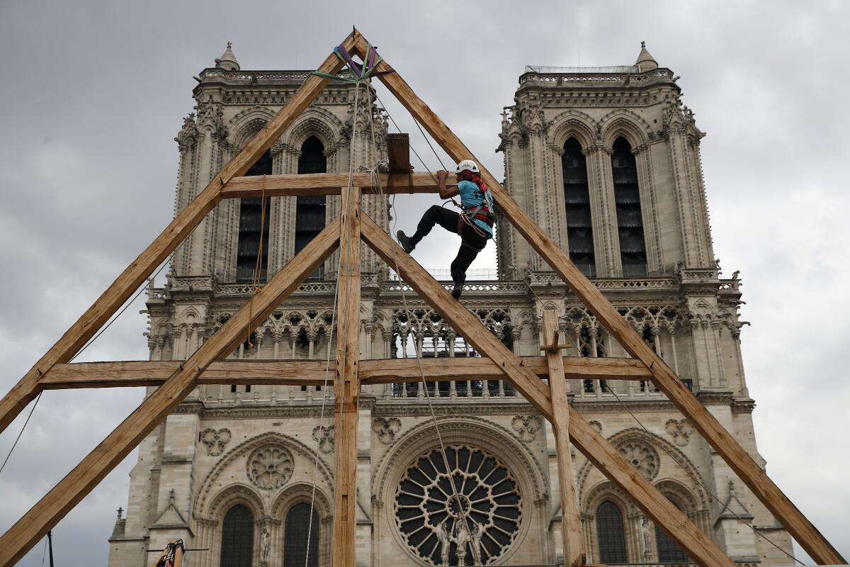 A carpenter works on a wooden framework high above ground level at Notre Dame Cathedral 
