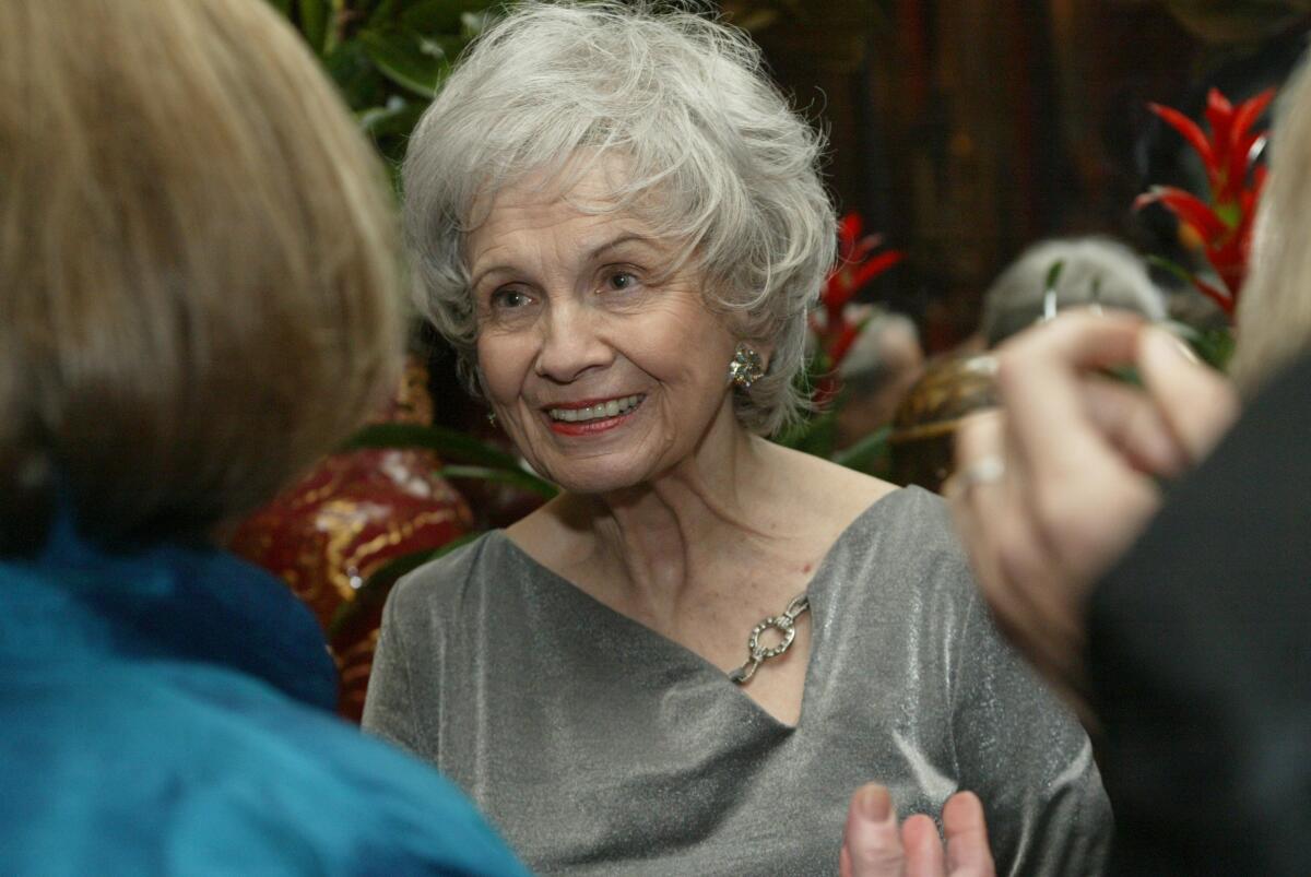 Alice Munro smiles in a shiny dress as she talks to a group 