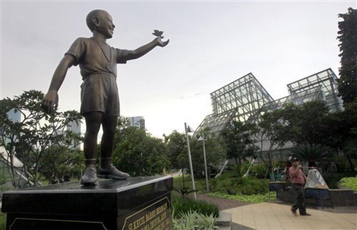 A food vendor walks past by the statue of U.S. President Barack Obama as a 10-year-old boy at Menteng Park in Jakarta, Indonesia, Tuesday, Feb. 2, 2010. Obama will take his family on a journey back to his boyhood in Indonesia, where he played games on the sweltering tropical streets of the capital and learned a foreign language. (AP Photo/Dita Alangkara)