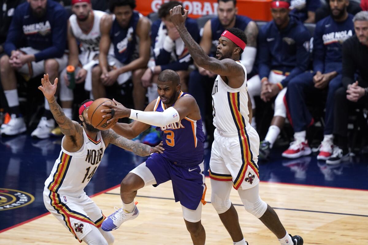 Phoenix Suns guard Chris Paul goes to the basket between New Orleans Pelicans forwards Brandon Ingram and Naji Marshall.