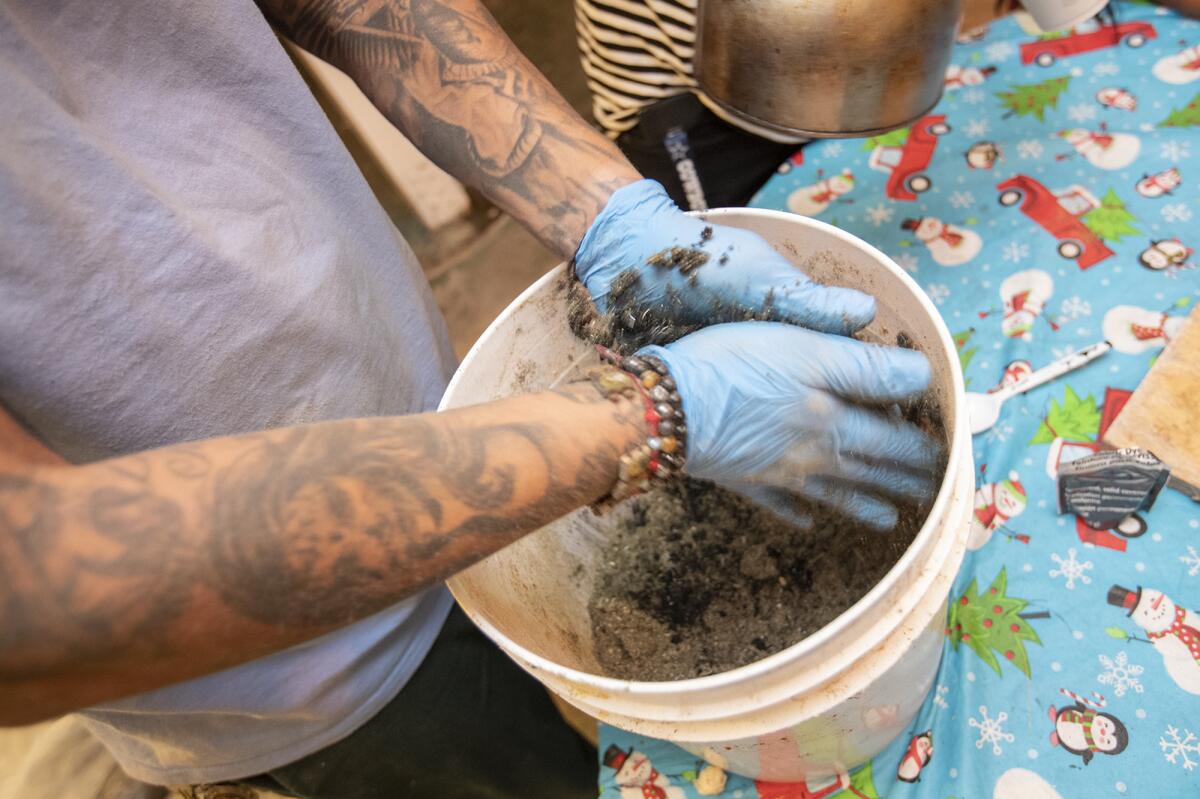 Efran Garcia mixes dried sawdust with food coloring in preparation to make a traditional carpet (tapete de arena) for the Day of the Dead celebration.