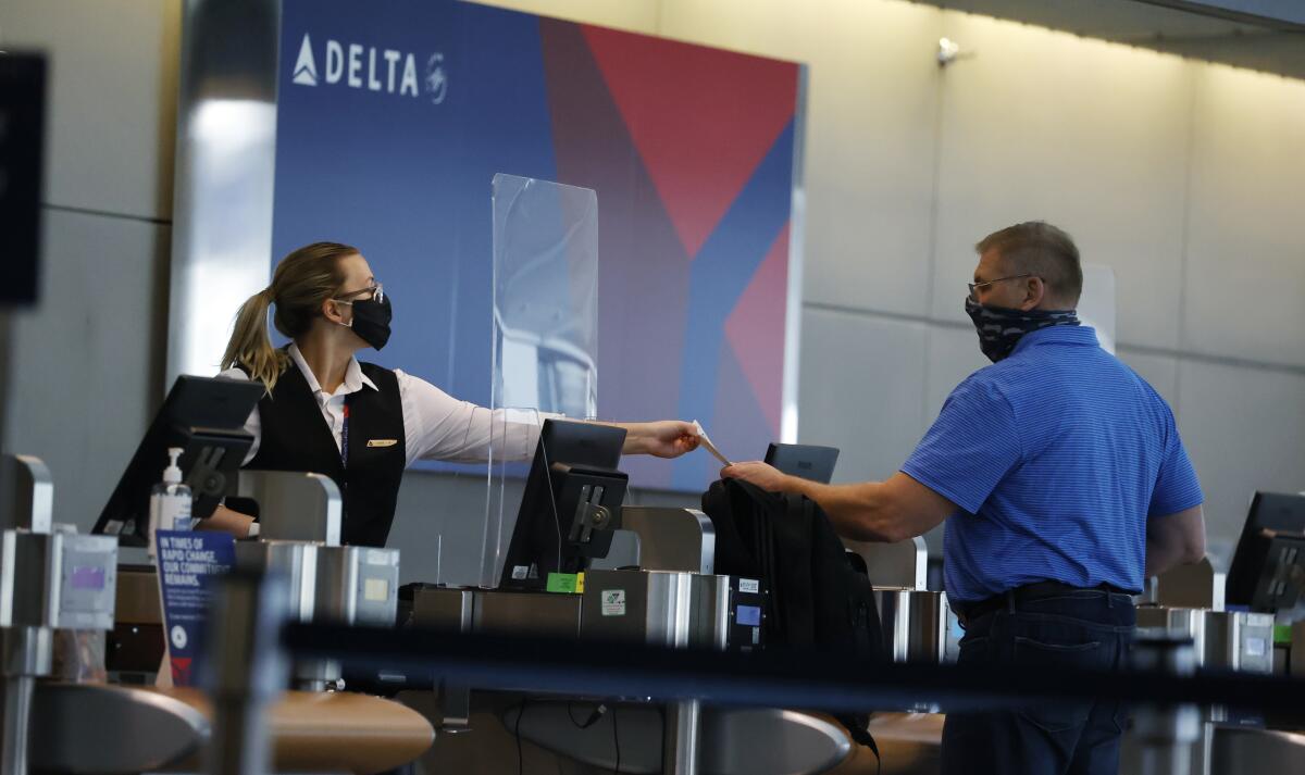 Delta Air Lines worker hands a boarding pass to a passenger