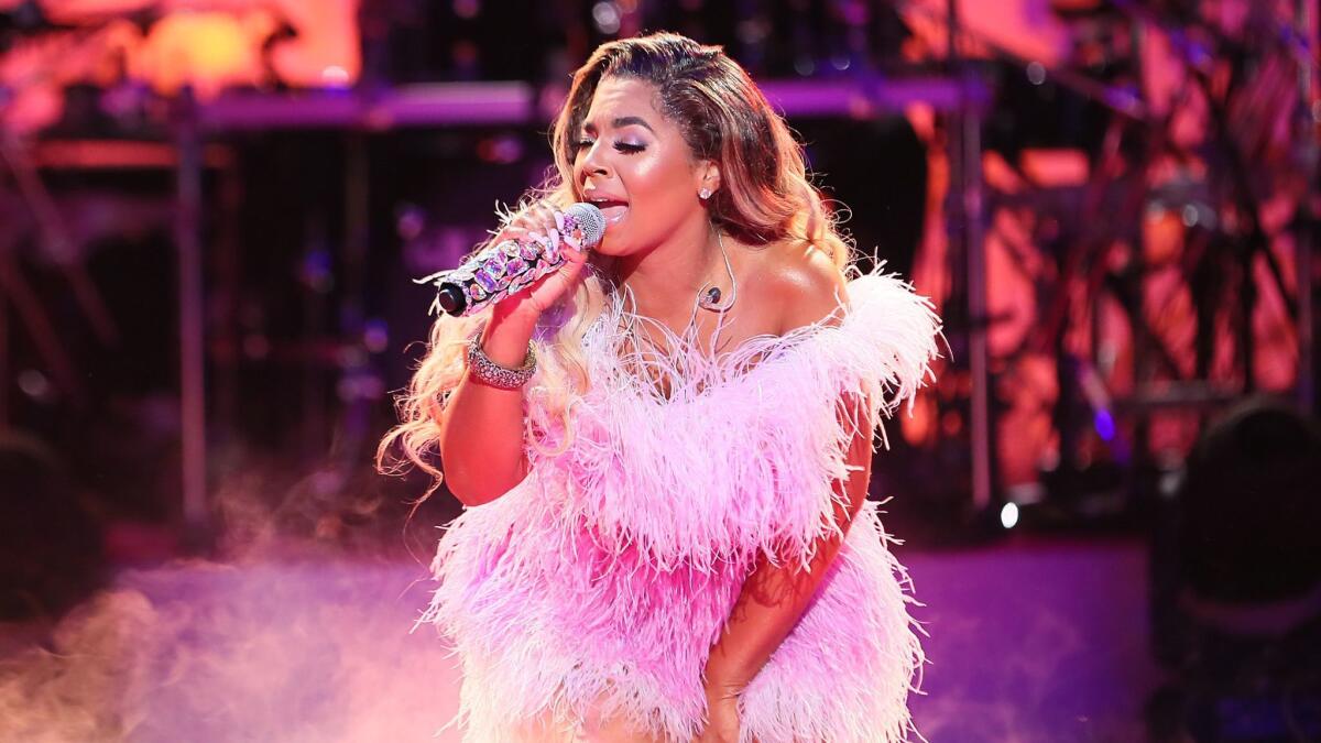 Ashanti singing onstage in a frilly pink dress.