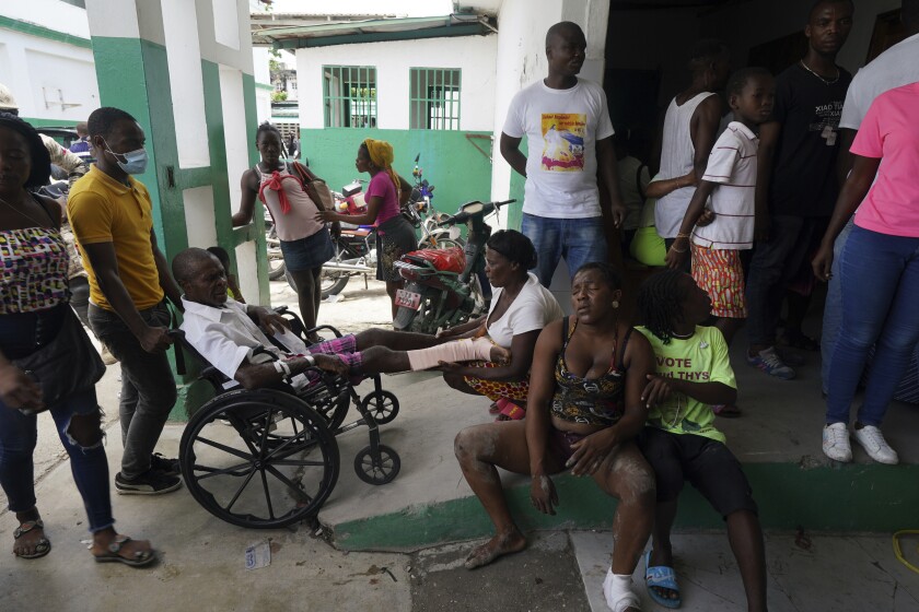 A group of people, one in a wheelchair, wait for treatment outside a hospital in Haiti.