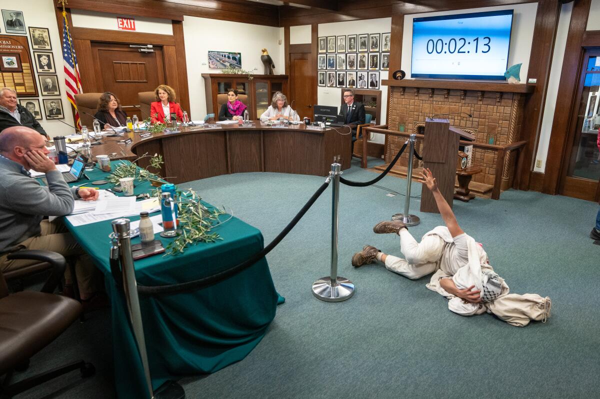 A man lies on the floor at a meeting.