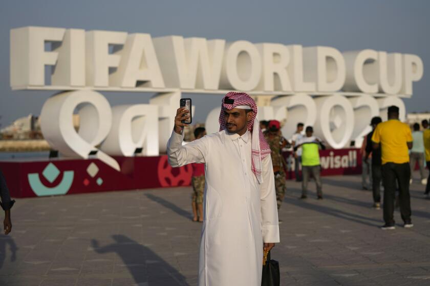 FILE - A man takes a selfie with a sign reading in English" Fifa World Cup, Qatar 2022" at the corniche in Doha, Qatar, Friday, Nov. 11, 2022. With no soccer tradition but billions in oil money, Qatar is the latest Persian Gulf nation using sports to try to burnish its image on the global stage. The host of the 2022 World Cup is smaller than Connecticut and has a population of fewer than 3 million. (AP Photo/Hassan Ammar, File)