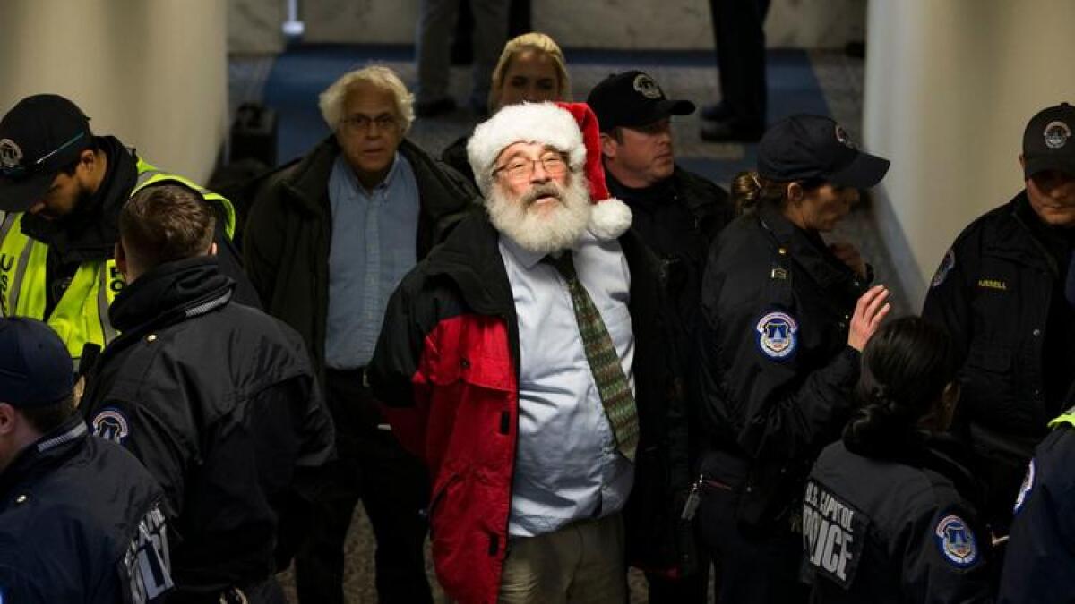 U.S. Capitol Police arrest a man wearing a Santa Claus hat during a protest against the Republican tax bill.