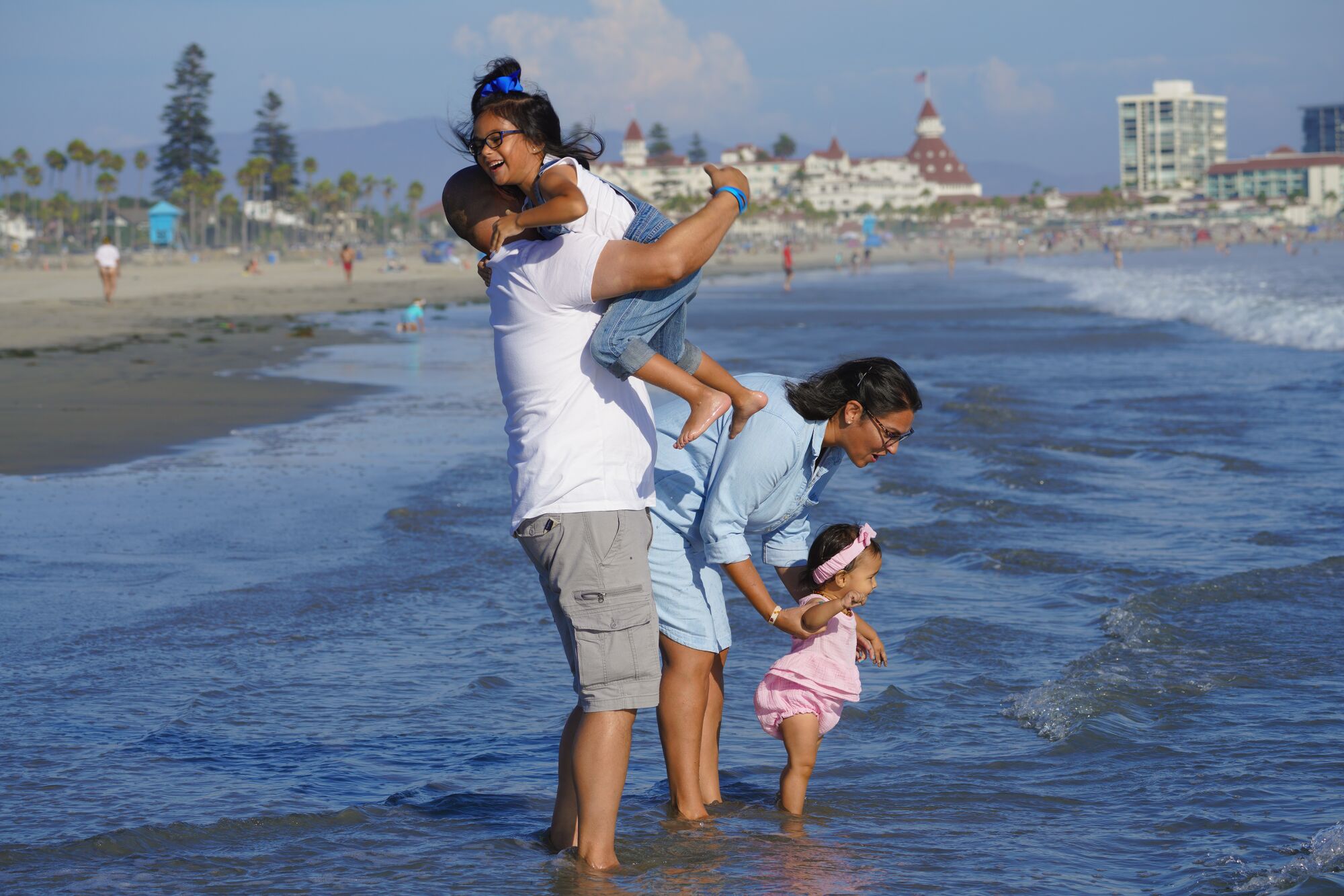 Una familia con dos hijas pequeñas juega en el agua en una playa