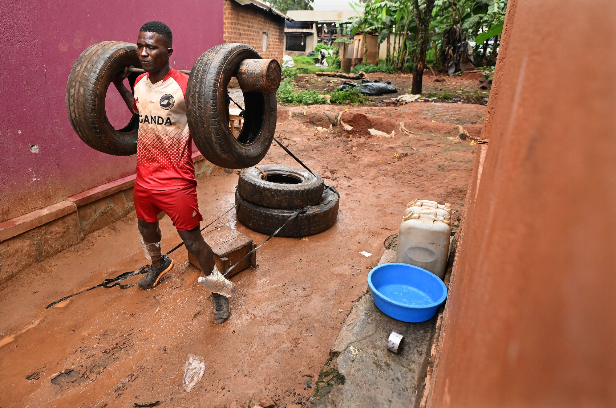 Dennis Kasumba works out with old tires outside his home