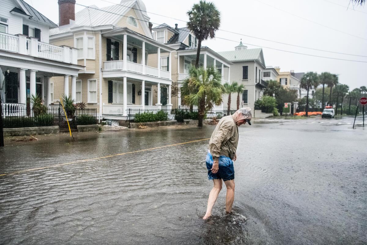 Bill Olesner walks down a flooded South Battery Street in Charleston, S.C., while cleaning debris from storm drains.