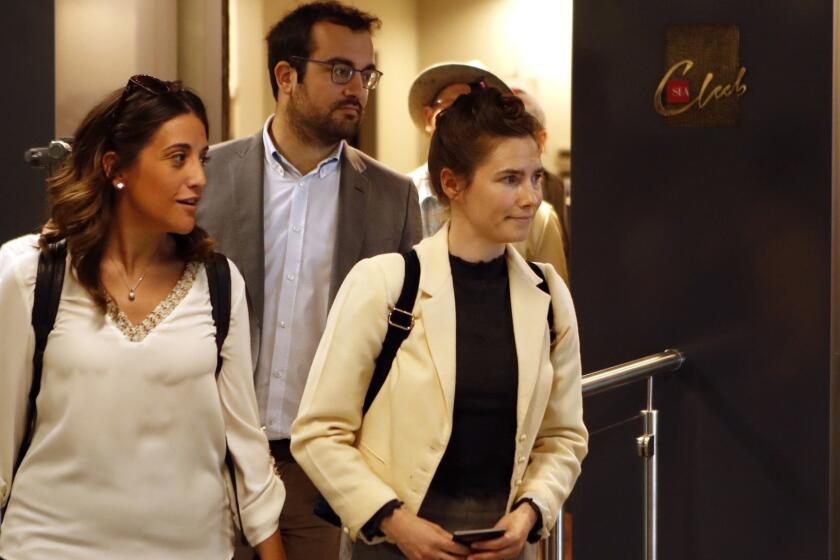 Amanda Knox, right, exits the airport from a side entrance upon her arrival in Linate airport, Milan, Italy, Thursday, June 13, 2019. Knox has returned to Italy for the first time since she was convicted and imprisoned, but ultimately acquitted, for the murder and sexual assault of her British roommate Meredith Kercher in the university town of Perugia in 2007. Knox is in Italy to attend a conference in Modena organized by the Italy Innocence Project, which seeks to help people who have been convicted for crimes they did not commit. (AP Photo/Antonio Calanni)