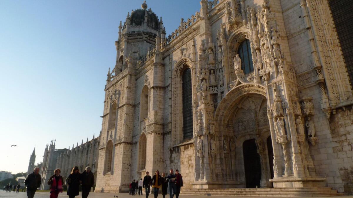 People walk past the 16th century Jeronimos Monastery in Lisbon.