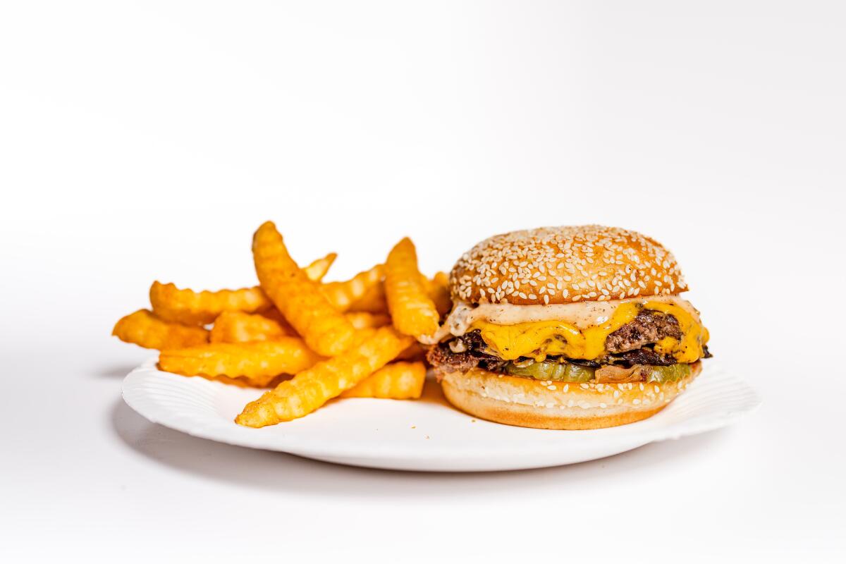 A cheeseburger and fries sit on a white plate.