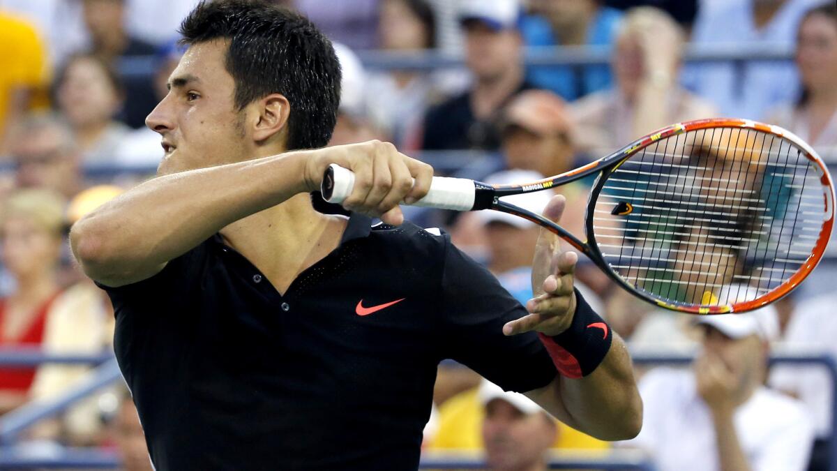 Bernard Tomic follows through on a shot against Lleyton Hewitt during their second-round match at the U.S. Open on Thursday.