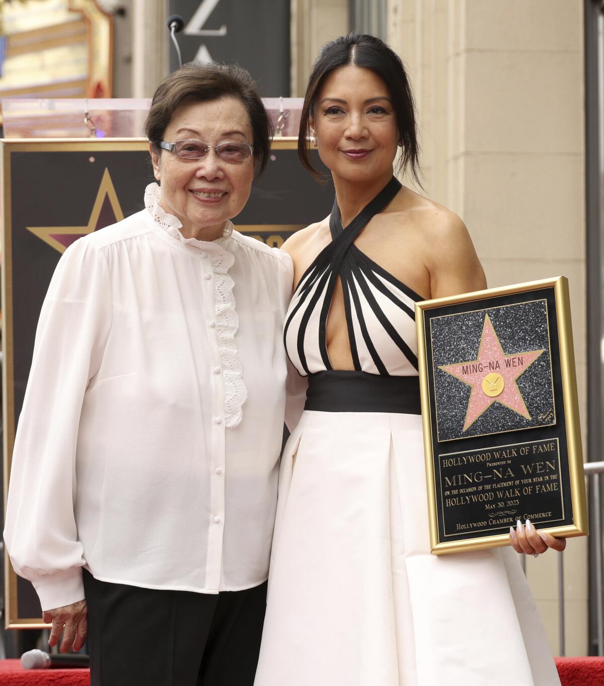 Ming-Na Wen in a white dress with black accents, stands beside her mom.