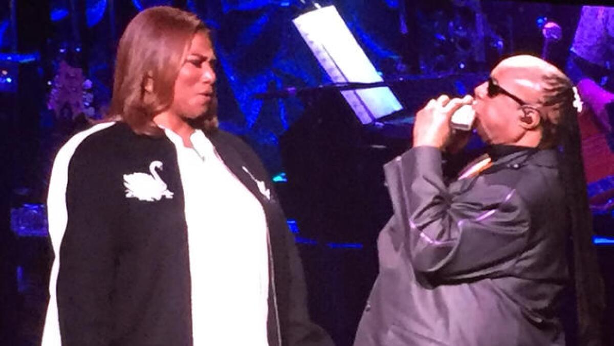 Queen Latifah marvels at Stevie Wonder's harmonica solo during one of her numbers at Wonder's 20th anniversary House Full of Toys benefit concert at the Microsoft Theatre in Los Angeles.