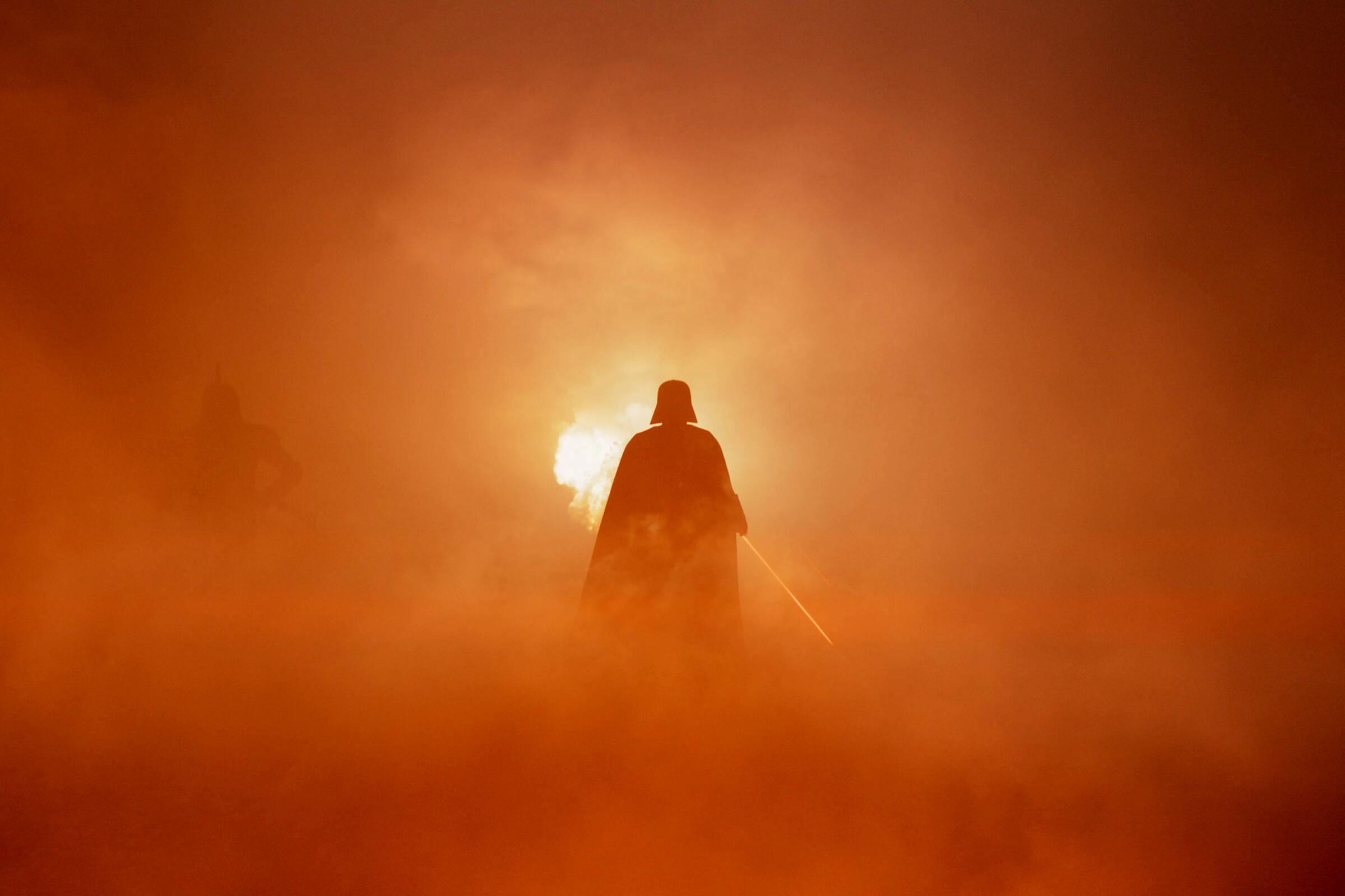 A silhouette of Darth Vader emerges from a reddish fog in "Star Wars: Ahsoka."