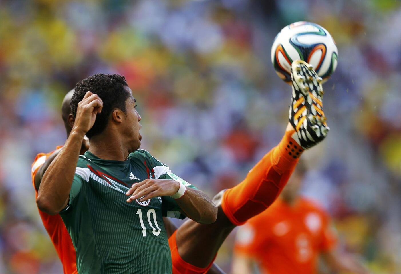 Mexico's Dos Santos fights for the ball with Martins Indi of the Netherlands during their 2014 World Cup round of 16 game at the Castelao arena in Fortaleza