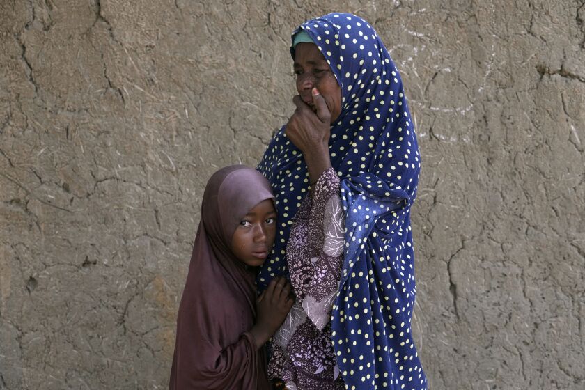Aisha Ali, 40, cries as she and her daughter Husseina, 9, wait in Tabawa, northeastern Nigeria, for four her or children to be prepared for burial Wednesday Oct. 26, 2022. When floodwaters reached her hut made of woven straw mats and raffia palms, she packed up what belongings she could and set off on foot with her eight youngest children. "While the flood was trying to destroy things, we were trying to save ourselves," she said.(AP Photo/Sunday Alamba)
