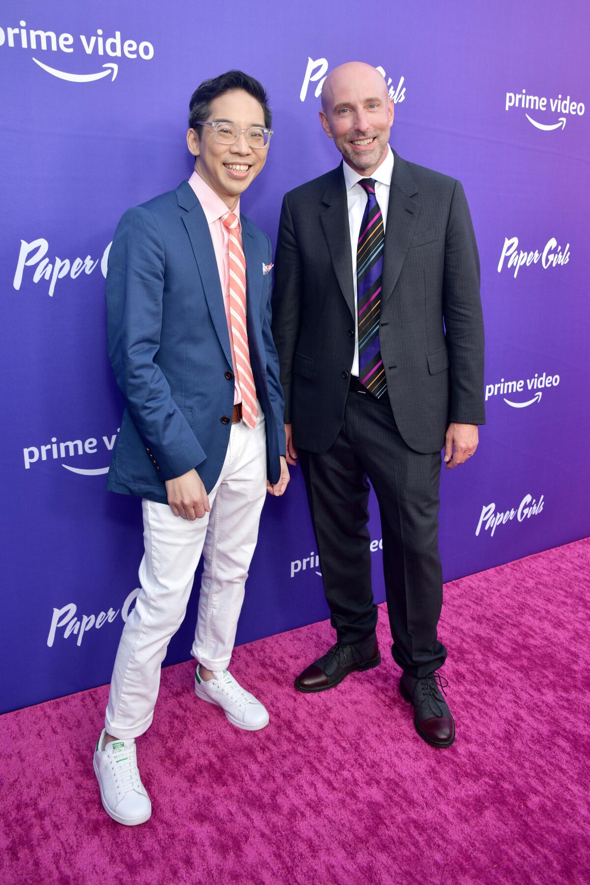 two men wearing suits on a red carpet