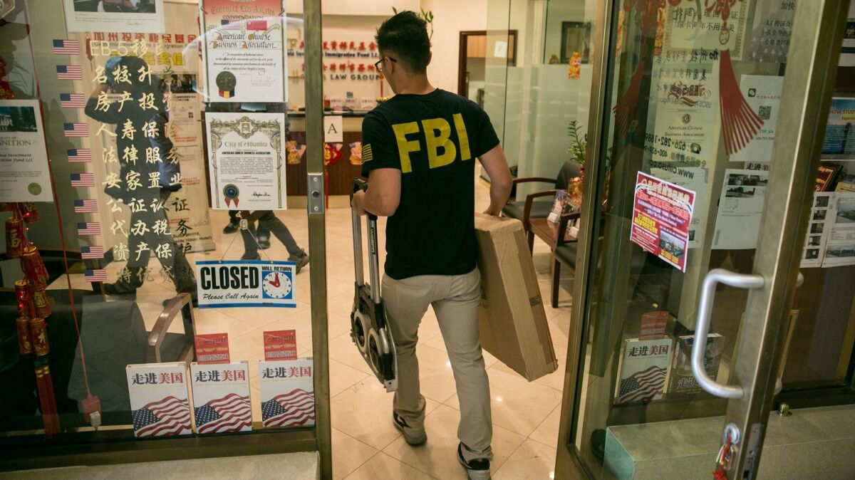 An FBI agent enters the lobby of the California Investment Immigration Fund/Harris Law Group on April 5, looking for evidence of visa.