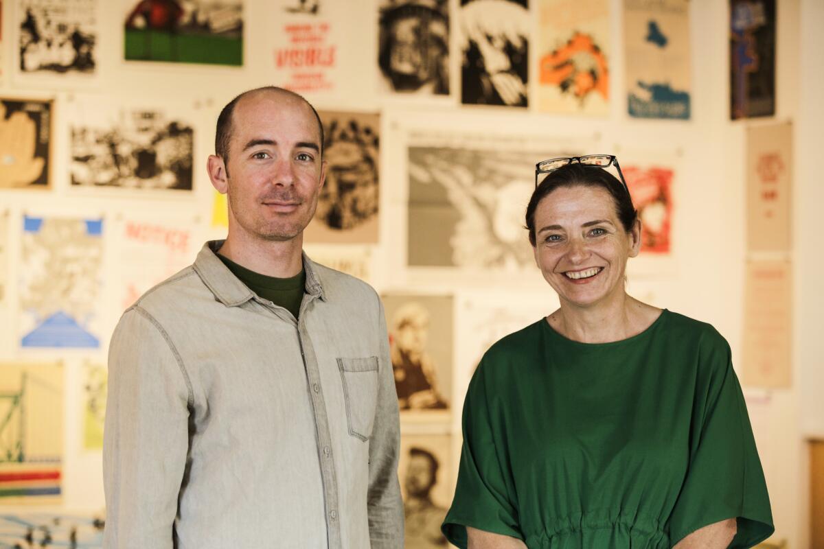 Artist Drew Cameron and gallerist Janet Owen Driggs stand inside "A Different 1%" exhibition at Cypress College.