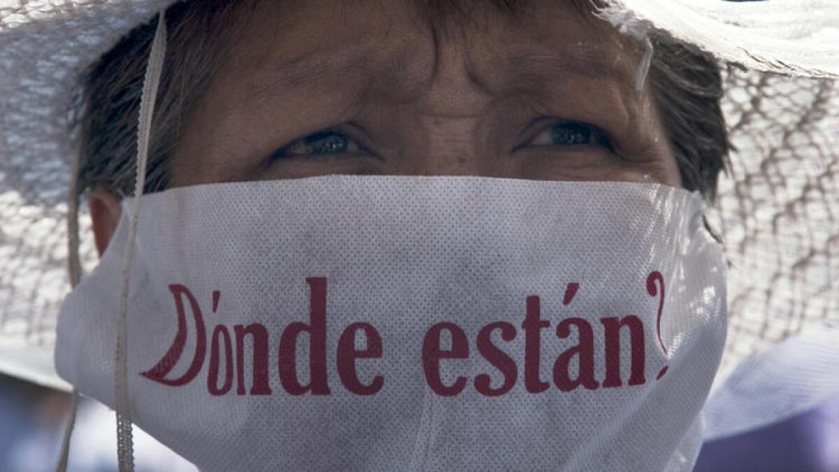 Una madre con una mascarilla que dice “¿Dónde están?” marcha junto con cientos de otras madres que sostienen imágenes de sus familiares desaparecidos, el domingo durante el día de las madres en la ciudad de México.