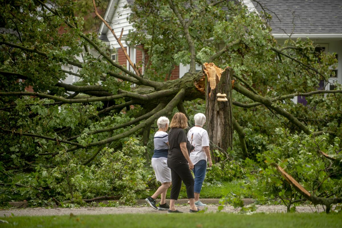 Flushing residents Donna Black, from left to right, Brenda Nyquist and Judy Doyle looks at the damage around their neighborhood as they check in with neighbors health and well-being on Thursday, Aug. 12, 2021 in Flushing, Mich., after a wave of strong storms ravaged neighborhoods in parts of Genesee County on Wednesday night. Heavy rains are bringing flooding to parts of Michigan, as waves of thunderstorms make their way across the Midwest. (Jake May/The Flint Journal via AP)