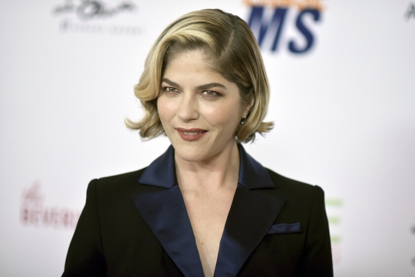 A woman with short blond hair posing in a black suit