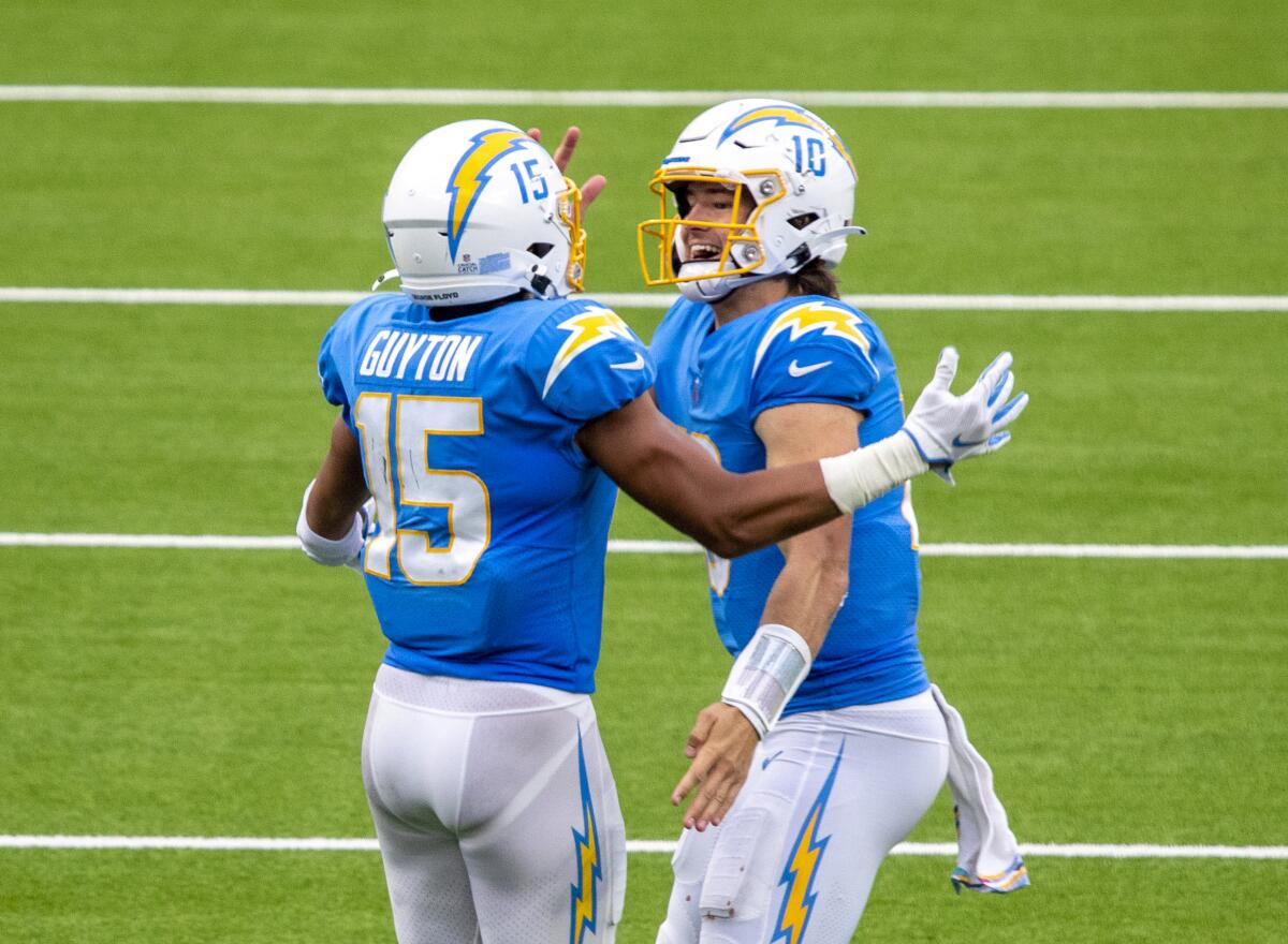 Chargers quarterback Justin Herbert, right, celebrates with Jalen Guyton after he caught Herbert's 70-yard touchdown pass.
