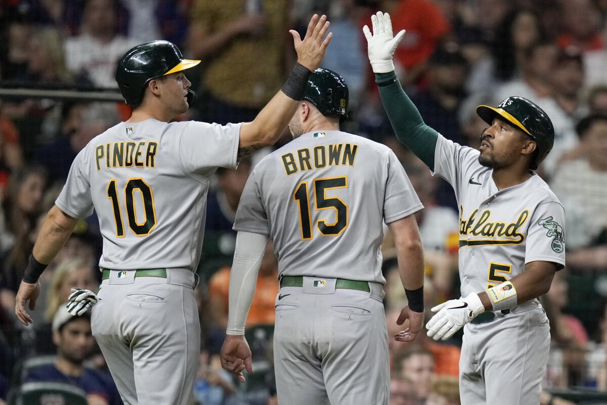 Oakland Athletics' Chad Pinder (10) celebrates with Tony Kemp, right, after scoring during the seventh inning of the team's baseball game against the Houston Astros, Friday, July 15, 2022, in Houston. (AP Photo/Eric Christian Smith)