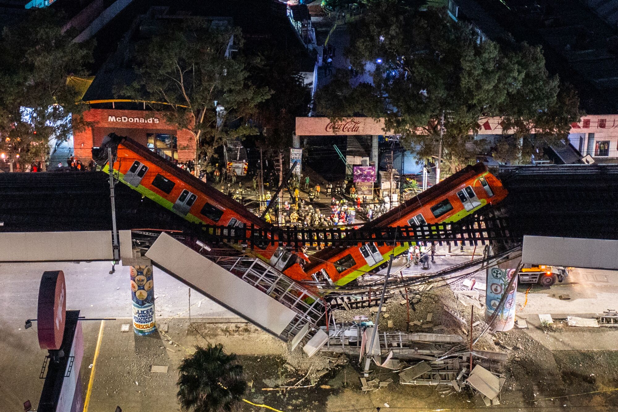 Two train cars hang off a collapsed elevated track.