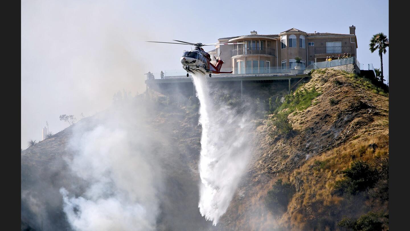 A Los Angeles City Fire Department water-dropping helicopter makes a drop near a home on the 2700 block of Howard Ct. in Burbank on Wednesday, June 28, 2017.