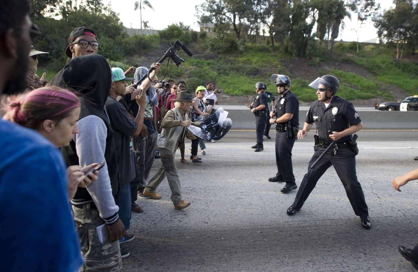 Police officers confront protesters on the 10 Freeway.