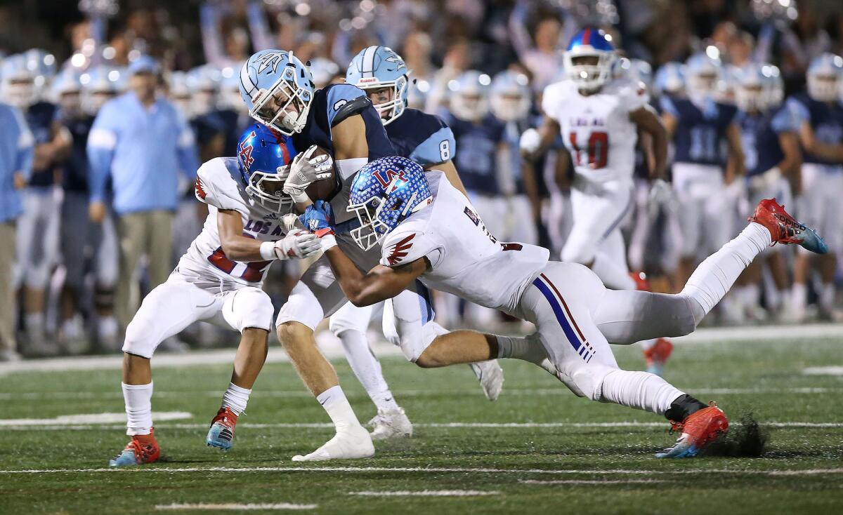 Corona del Mar's Tommy Griffin returns an interception for a long gain and is brought down by Los Alamitos' Gavin Porch, left, and Giovanni De Leon in a Sunset League game at Davidson Field on Friday.